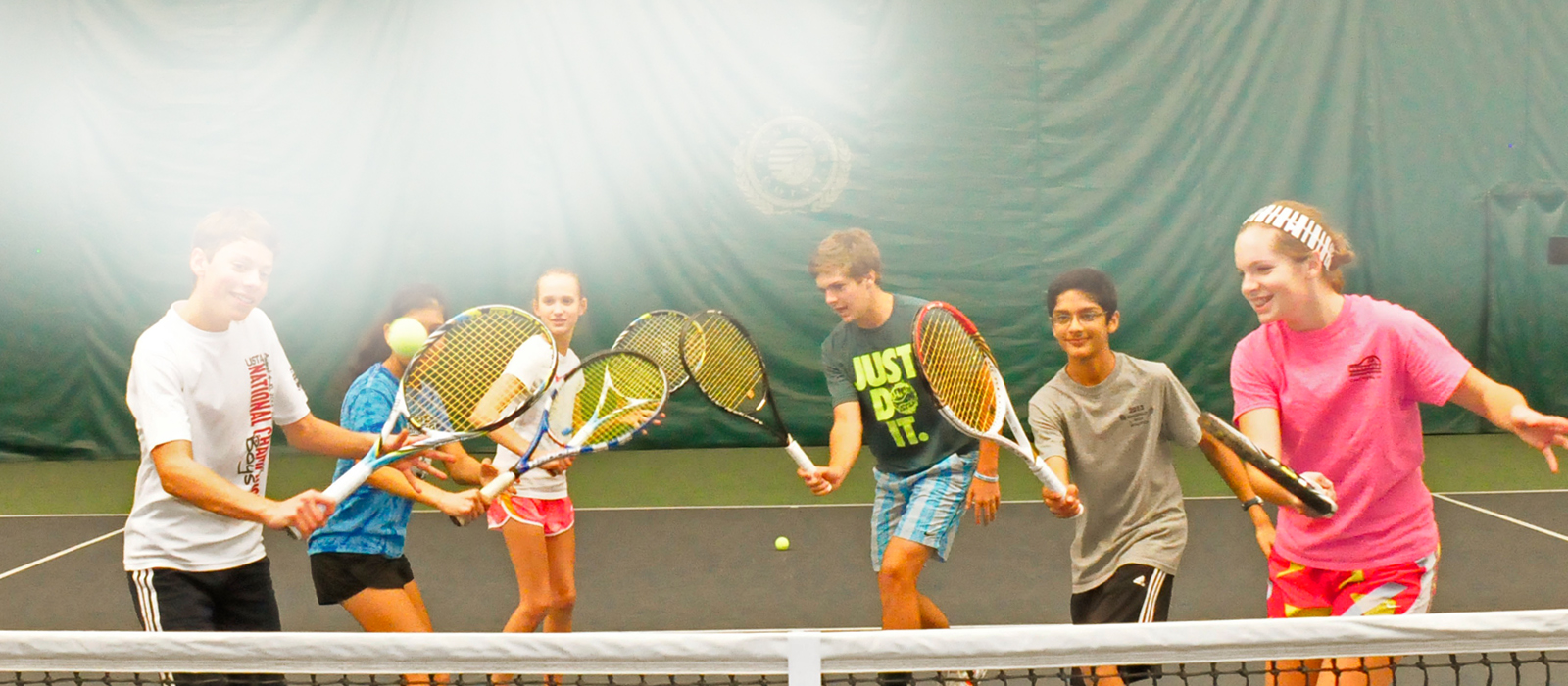 children practicing their tennis swings on tennis court
